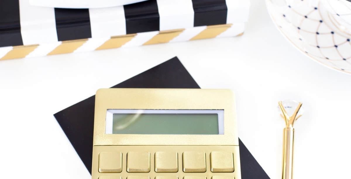 Gold calculator on desk with black and white accessories