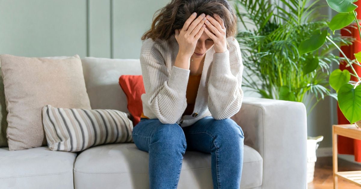 Lady sitting on sofa with head in hands