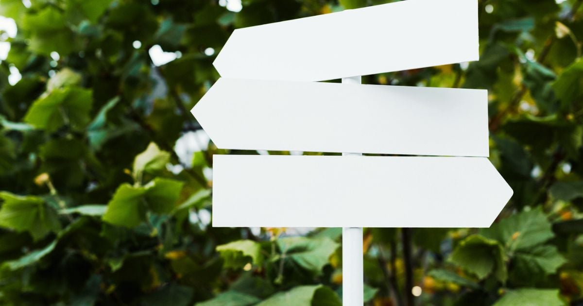 Set of white road signs with trees in background