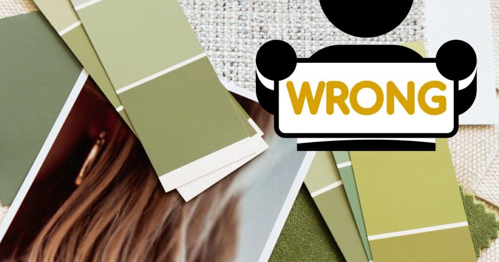 Room designing items including paint charts and photographs, on a table with a cartoon person holding a sign saying 'WRONG' over it