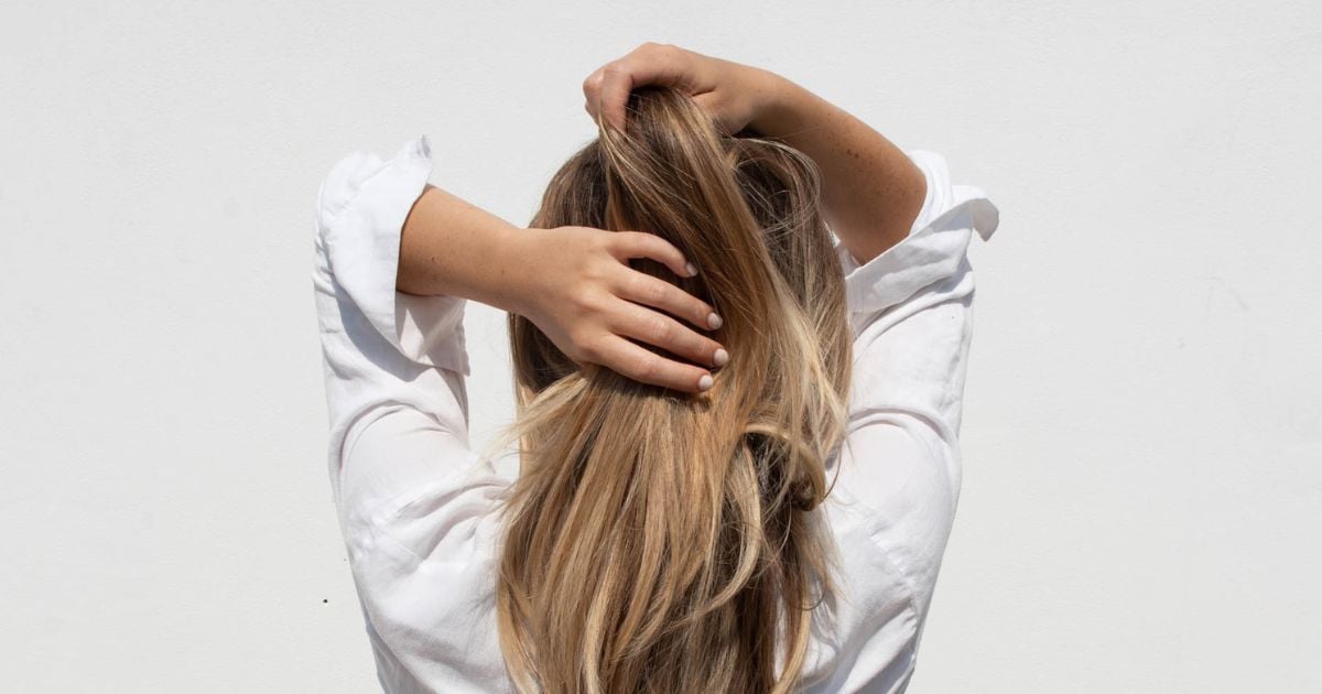 Lady facing away from camera with her hads going through her hair on the back of her head - like shes a bit stressed
