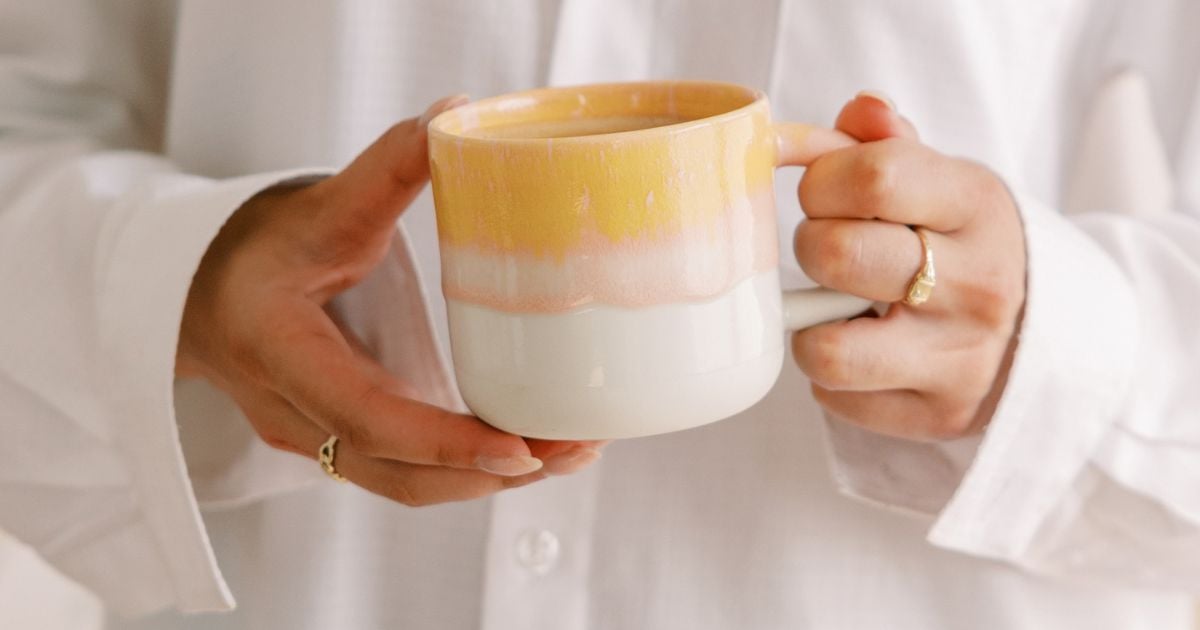 Closeup of lady holding a yellow and white mug with both hands