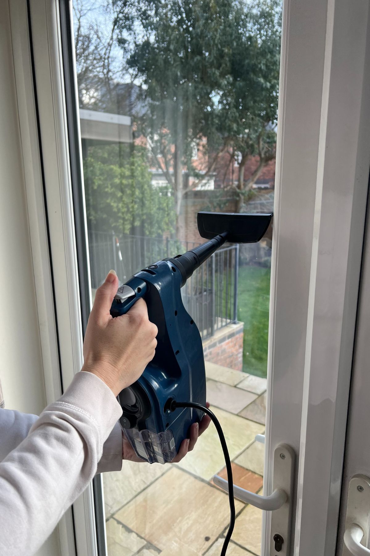 Hand held steam cleaner being used to clean windows