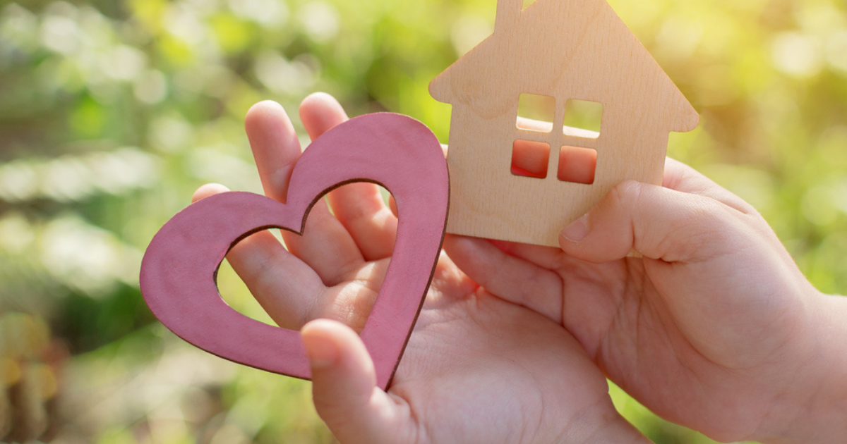 Hands holding a heart and a house made of wood