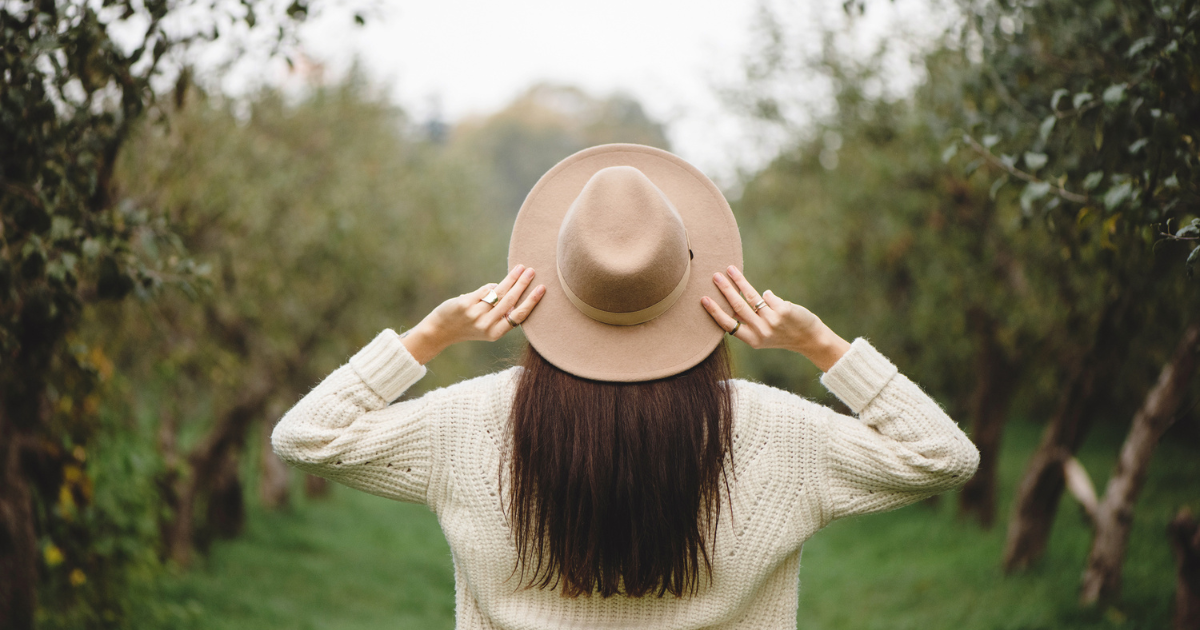 Feel Good Home Pic - Lady facing away from camera with hands on her sun hat