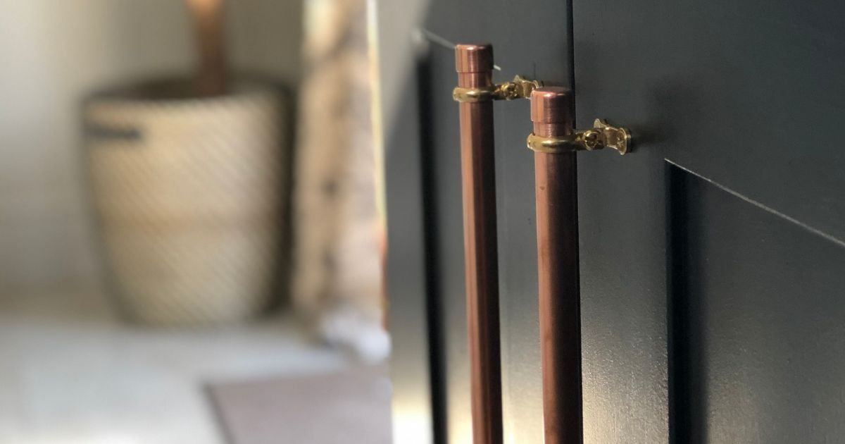 Close up of kitchen cupboards painted black with copper handles