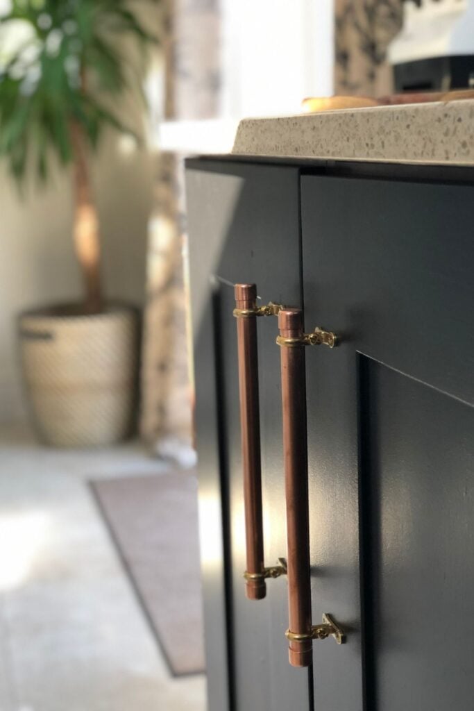 Kitchen units after being painted black - with copper handles