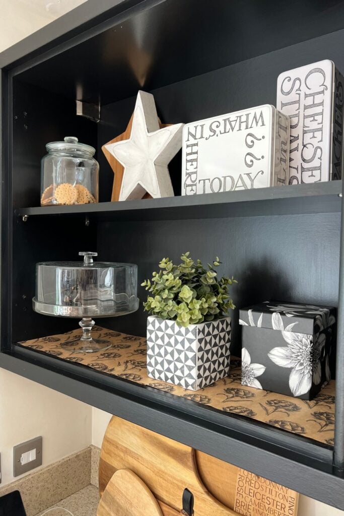 Close up of kitchen wall cabinet painted black and having doors taken off to create shelves