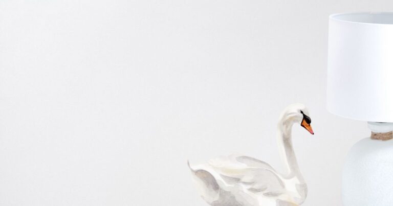 Swan on neutral background with white standard lamp to the right