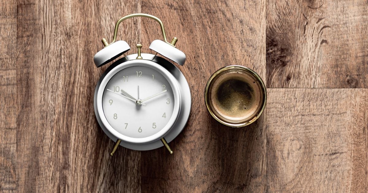 Alarm clock on it's side and cup of coffee from above on a wooden surface