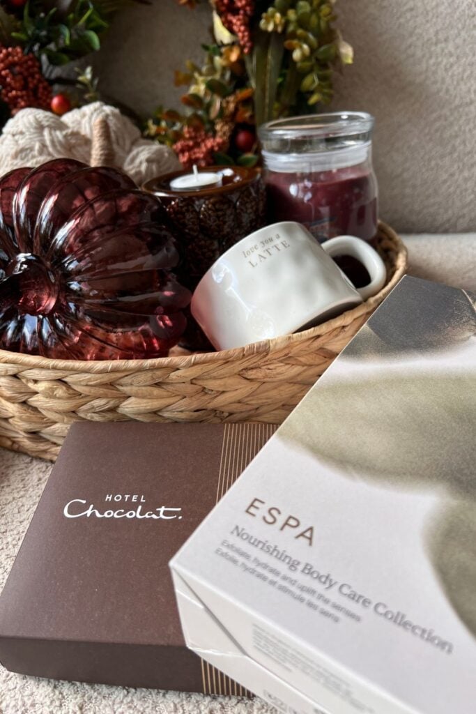 Boo basket tray with pumpkins, a set of tea light holders, a mug, a jar candle, and a selection of chocolates and toiletries in