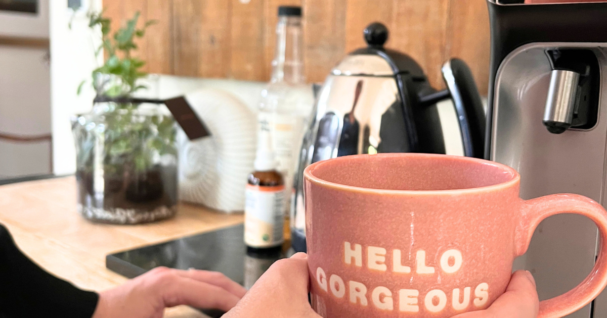 Getting a coffee ready at a coffee station with a pink mug saying 'hello gorgeoua'