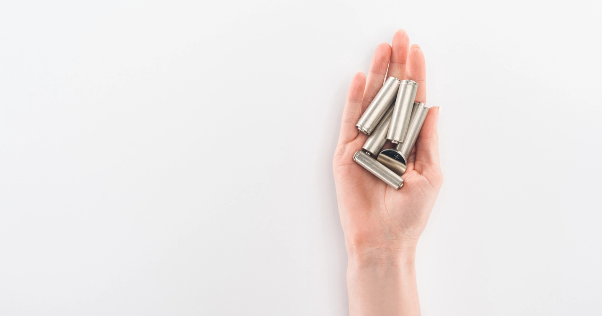 Hand holding several batteries of different sizes